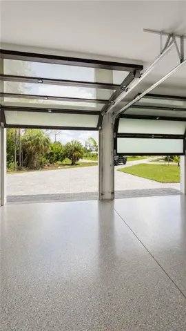 Garage featuring a polished epoxy floor, two overhead doors with translucent panels, and a paver driveway