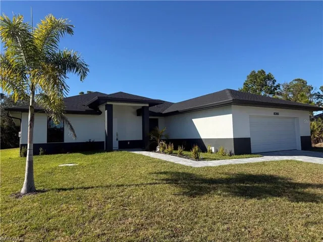View of front of house featuring a front yard, stucco siding, and a garage
