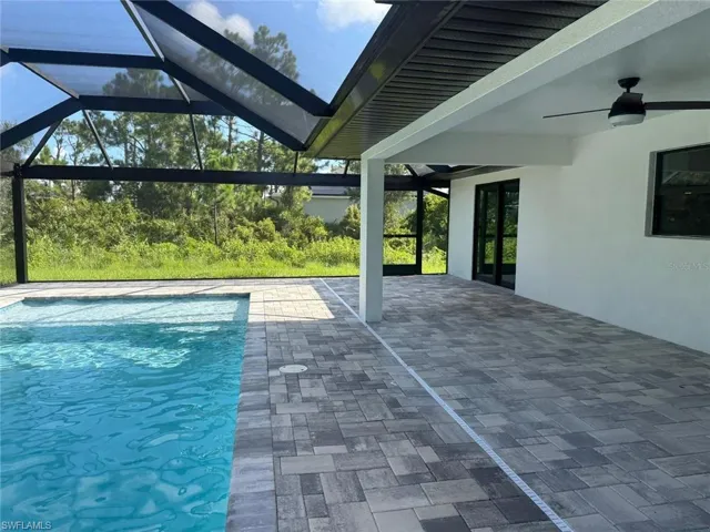 Outdoor pool with a lanai, a patio, and a sunroom