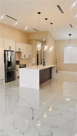 Contemporary kitchen featuring a spacious island with a waterfall countertop, white cabinetry with dark hardware, and glossy white tiled flooring