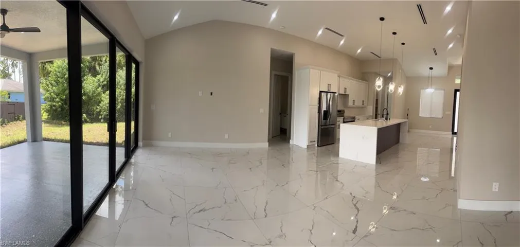 Expansive interior featuring large format marble-look tile flooring, vaulted ceilings, and recessed lighting
