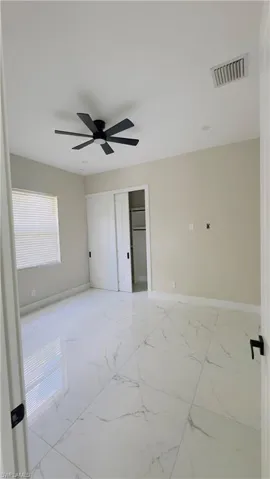 Spacious room featuring white large format tile flooring, a contemporary black ceiling fan, and recessed lighting