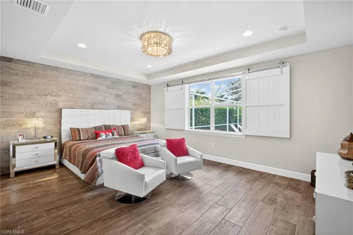 Bedroom with an accent wall, a tray ceiling, dark wood finished floors, and recessed lighting