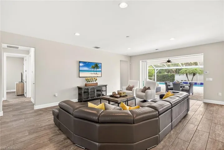 Living room with a sunroom, wood finish floors, and recessed lighting