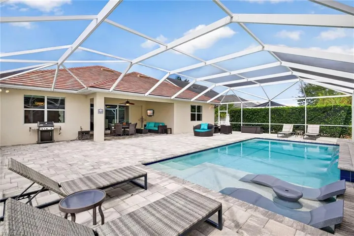 View of swimming pool featuring patio surround, a sunroom, glass enclosure, and area for grilling
