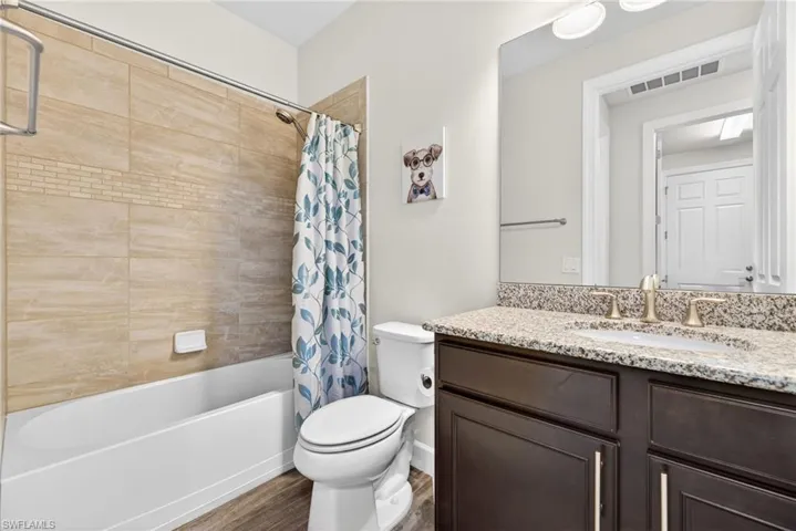 Bathroom with vanity, dark wood-type flooring, and shower / tub combo with curtain