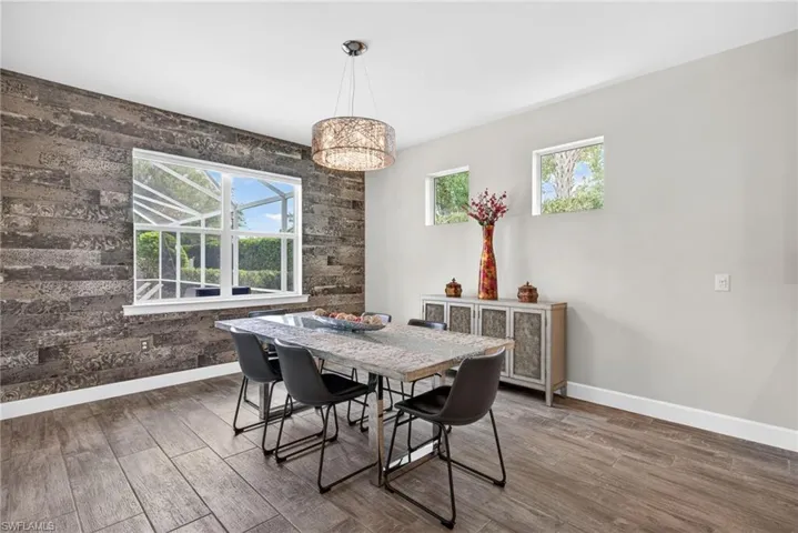 Dining space with dark wood-style floors and an accent wall