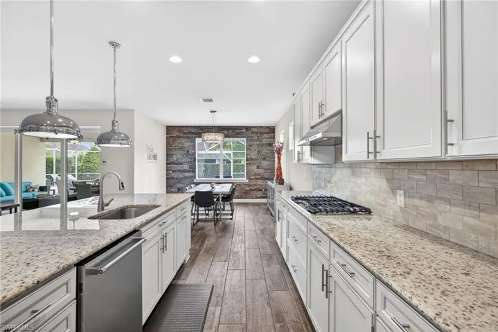 Kitchen with white cabinetry, stainless steel appliances, dark wood-style flooring, and light stone countertops