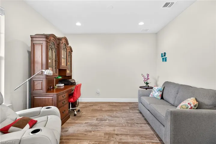 Den with light wood finished floors and recessed lighting