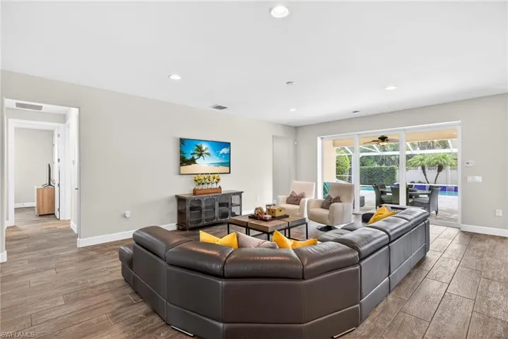 Living room with wood finished floors, recessed lighting, and a sunroom