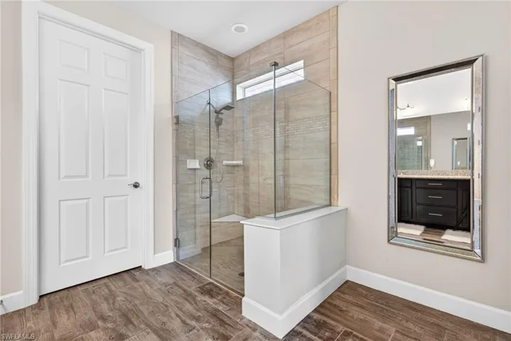 Bathroom with a stall shower, dark wood finished floors, and vanity