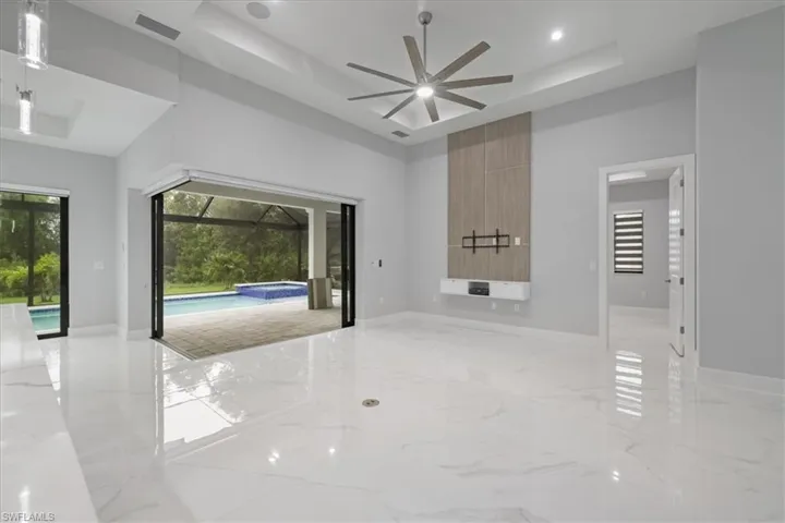 Spare room with a tray ceiling, a ceiling fan, a towering ceiling, light marble finish floors, and recessed lighting