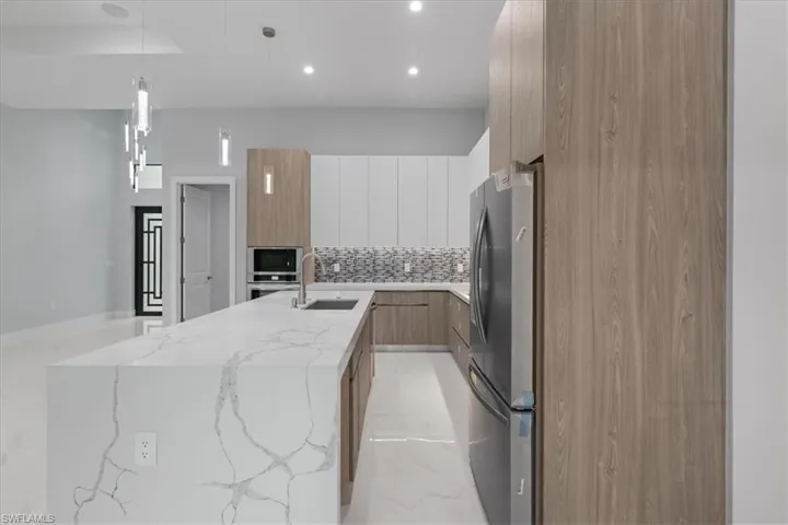 Kitchen featuring modern cabinets, stainless steel appliances, a kitchen island with sink, tasteful backsplash, and recessed lighting