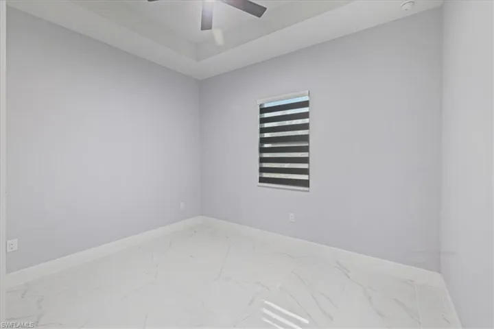 Unfurnished room featuring marble finish flooring, a ceiling fan, and a smoke detector
