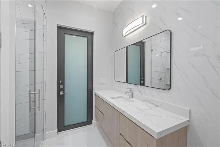 Bathroom featuring a marble finish shower, vanity, and marble finish flooring