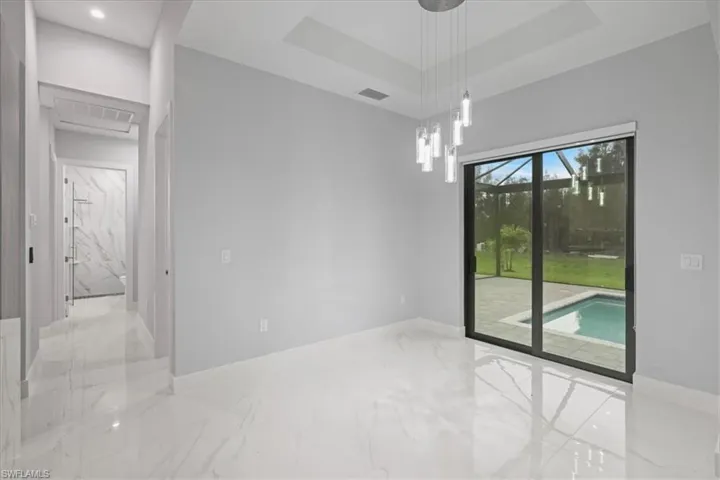 Unfurnished room featuring marble tiled flooring, a raised ceiling, and recessed lighting