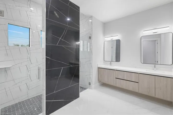 Full bathroom with double vanity, a marble finish shower, and marble finish flooring