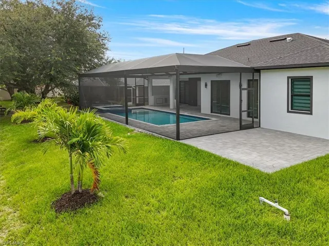 Rear view of house featuring a patio area, a yard, an outdoor pool, and stucco siding
