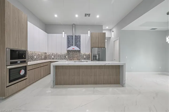 Kitchen featuring appliances with stainless steel finishes, modern cabinets, light marble finish floors, backsplash, and recessed lighting