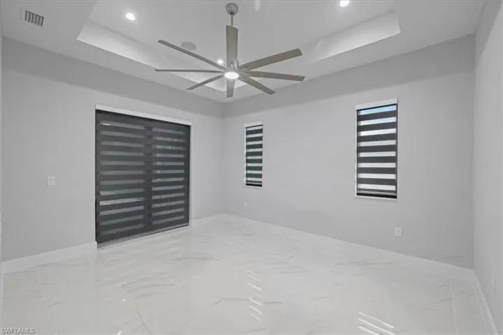 Spare room featuring a tray ceiling, ceiling fan, marble finish floors, and recessed lighting