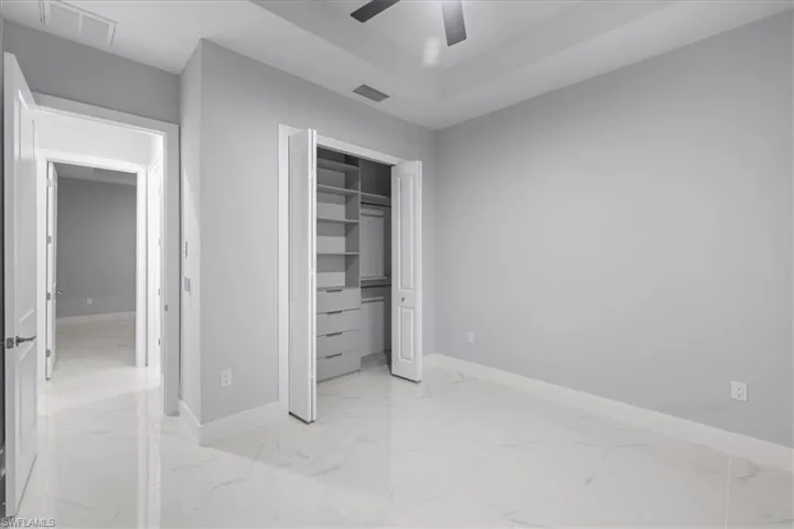 Unfurnished bedroom featuring light marble finish flooring, a closet, and ceiling fan