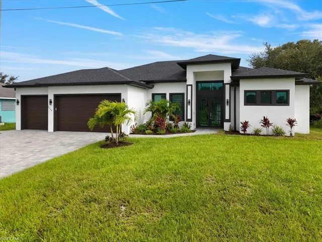 Prairie-style house featuring french doors, a garage, stucco siding, decorative driveway, and a front lawn