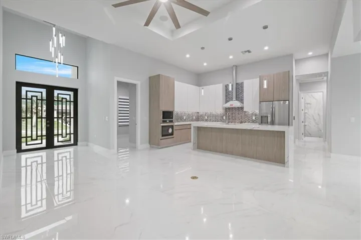 Kitchen featuring appliances with stainless steel finishes, modern cabinets, a ceiling fan, wall chimney exhaust hood, and recessed lighting
