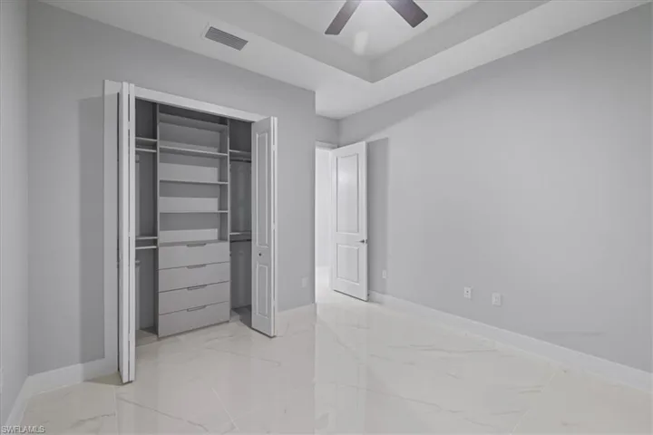 Unfurnished bedroom with light marble finish floors, a closet, and ceiling fan