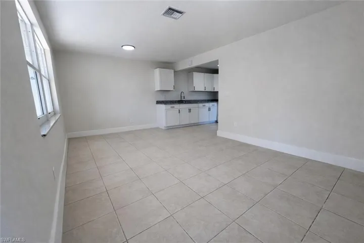 Unfurnished living room with light tile patterned floors and baseboards