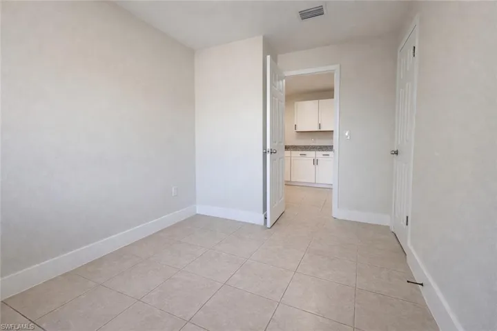 Unfurnished bedroom with light tile patterned floors and ensuite bath
