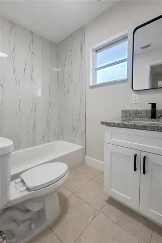 Bathroom with vanity, light tile patterned flooring, and bathing tub / shower combination