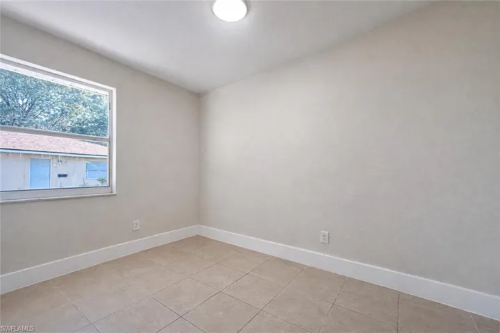 Empty room featuring baseboards and light tile patterned floors