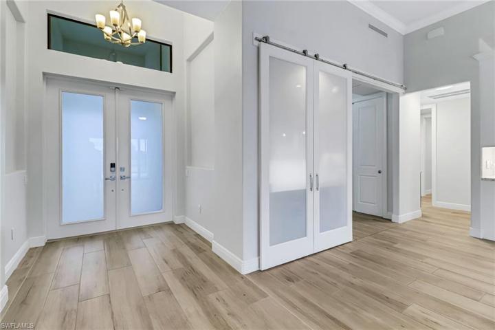 Double front doors (impact glass) transom window, and glass barn doors to office (currently covering the wet bar).