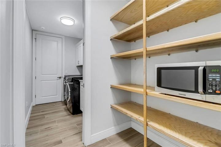Laundry room w/ additional cabinets and utility sink, and walk in pantry w/ oak shelving.
