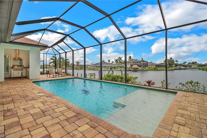 Heated salt water pool w/ custom sun shelf overlooking the water. Notice the summer kitchen in the upper left corner.