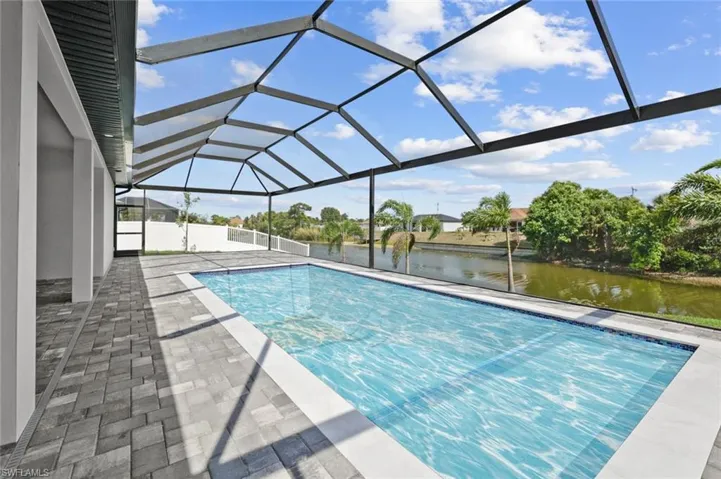 Swimming pool featuring a water view, a patio, and a lanai