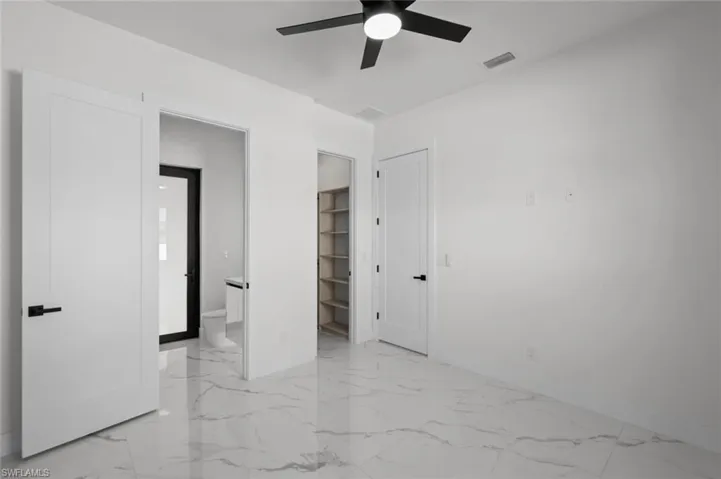 Unfurnished bedroom with light marble finish floors, baseboards, and ensuite bath