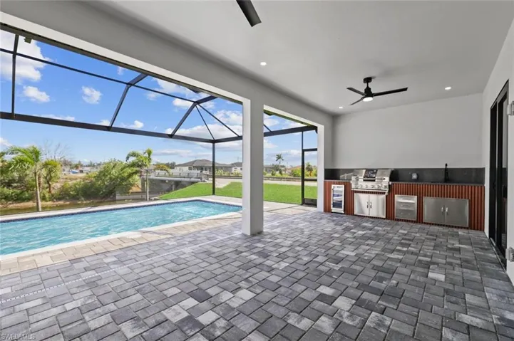 Outdoor pool featuring ceiling fan, a patio, and glass enclosure