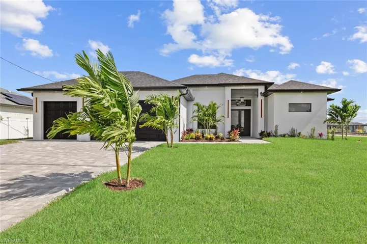 Prairie-style home featuring a garage, driveway, a front lawn, and stucco siding