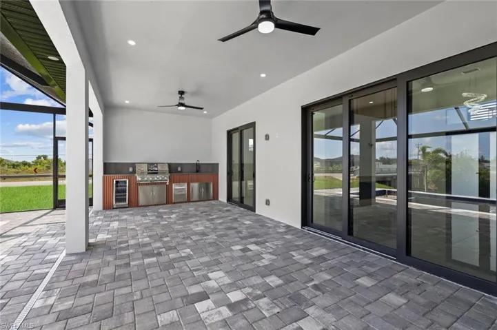 View of patio with ceiling fan, wine cooler, and a sink
