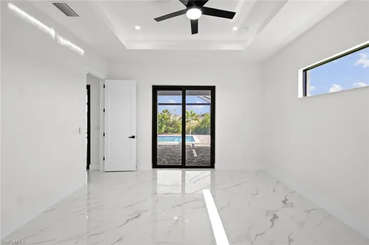 Empty room featuring a tray ceiling, marble tiled flooring, baseboards, plenty of natural light, and recessed lighting