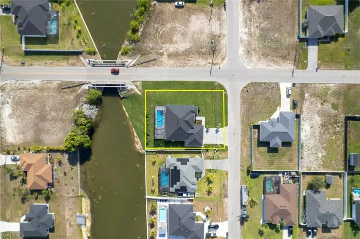 Aerial view of residential area featuring property boundaries highlighted and a large body of water