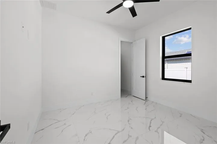 Unfurnished room with baseboards, ceiling fan, and marble look tiles