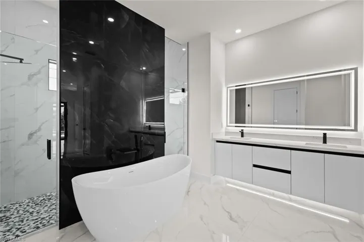 Bathroom with marble tiled flooring, a marble finish shower, a soaking tub, double vanity, and recessed lighting