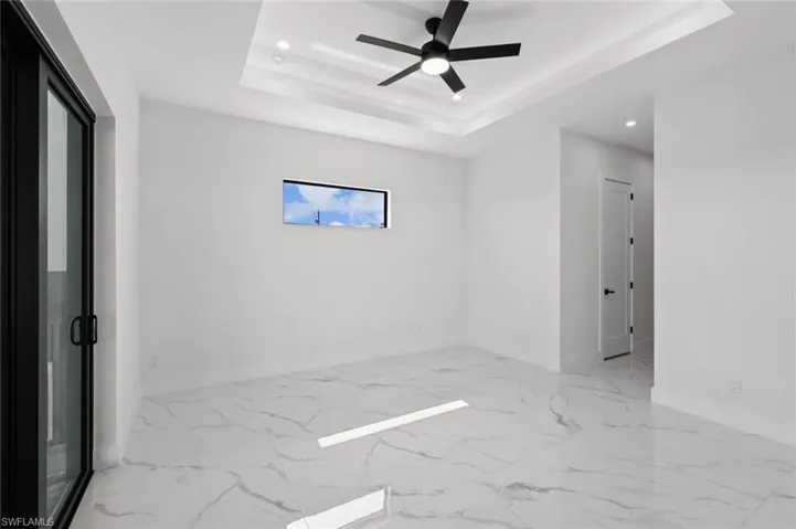 Spare room with recessed lighting, baseboards, a ceiling fan, a tray ceiling, and marble finish floors