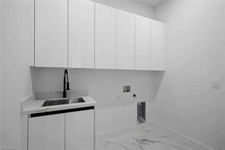 Laundry area with cabinet space, baseboards, hookup for a washing machine, electric dryer hookup, and marble finish floors