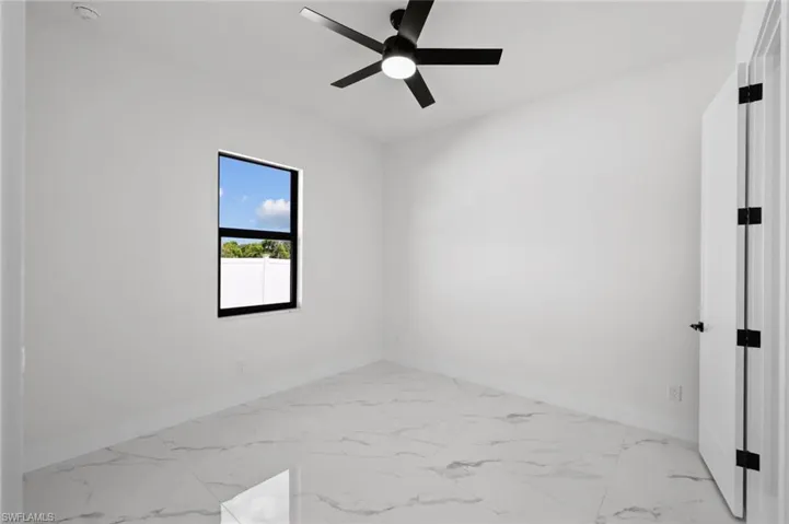 Spare room featuring baseboards, ceiling fan, and marble look tiles