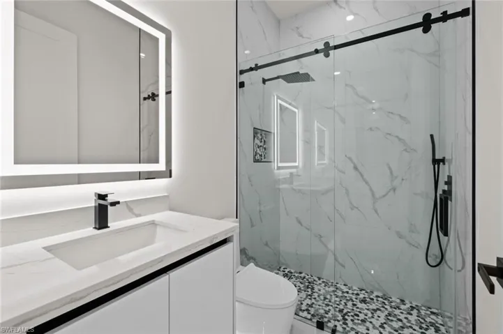 Bathroom featuring vanity, toilet, and a marble finish shower