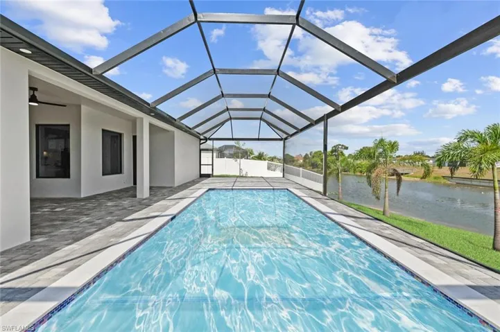 Outdoor pool featuring a water view, a patio area, and glass enclosure