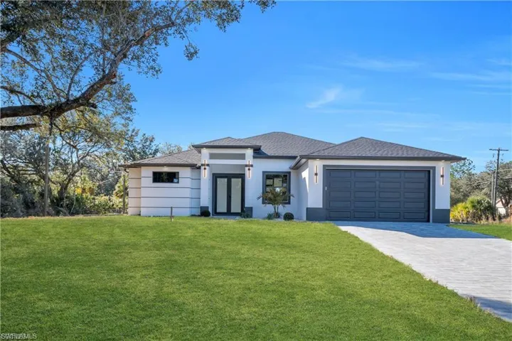Prairie-style house featuring a front yard, decorative driveway, an attached garage, and stucco siding